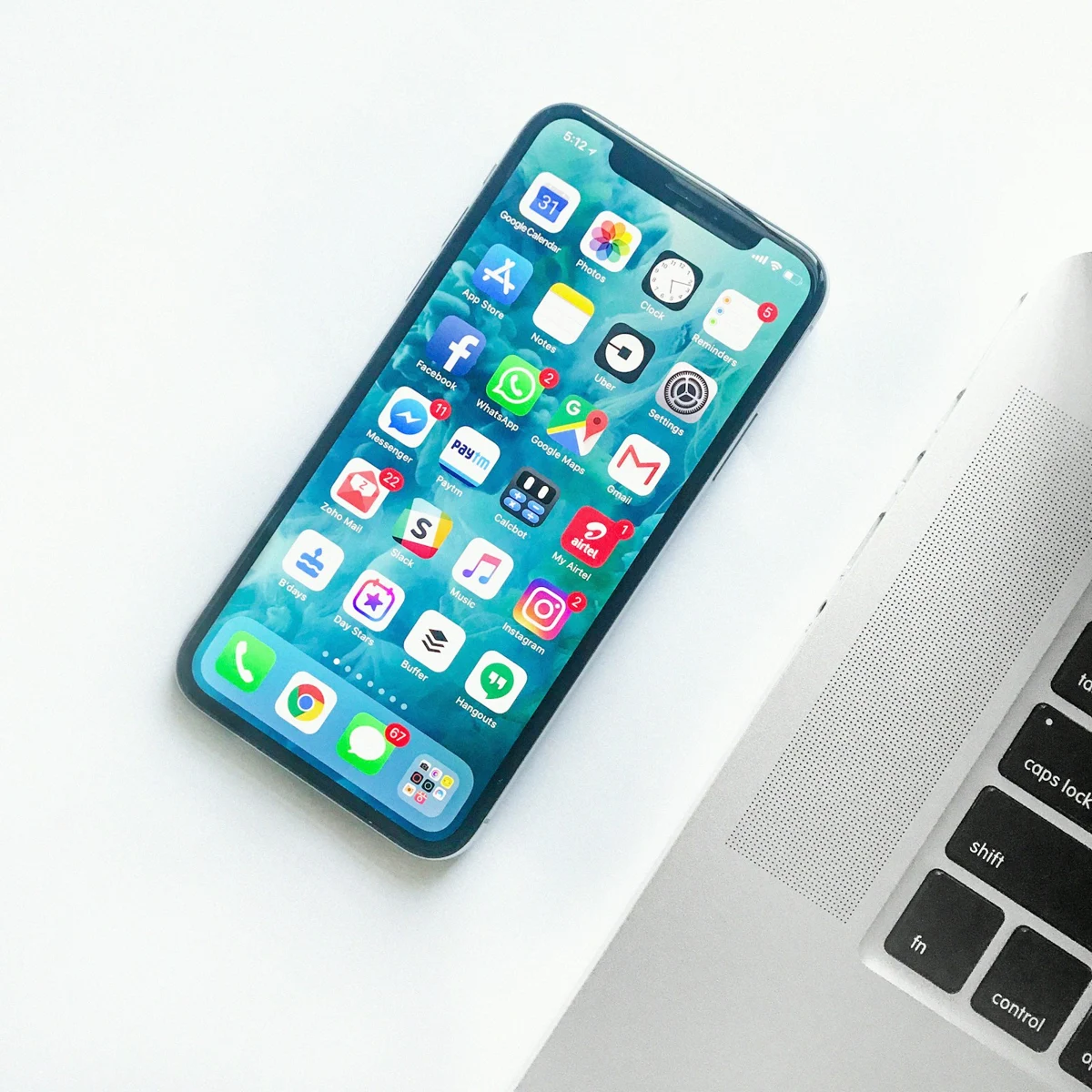 Smartphone displaying colourful app icons beside a laptop