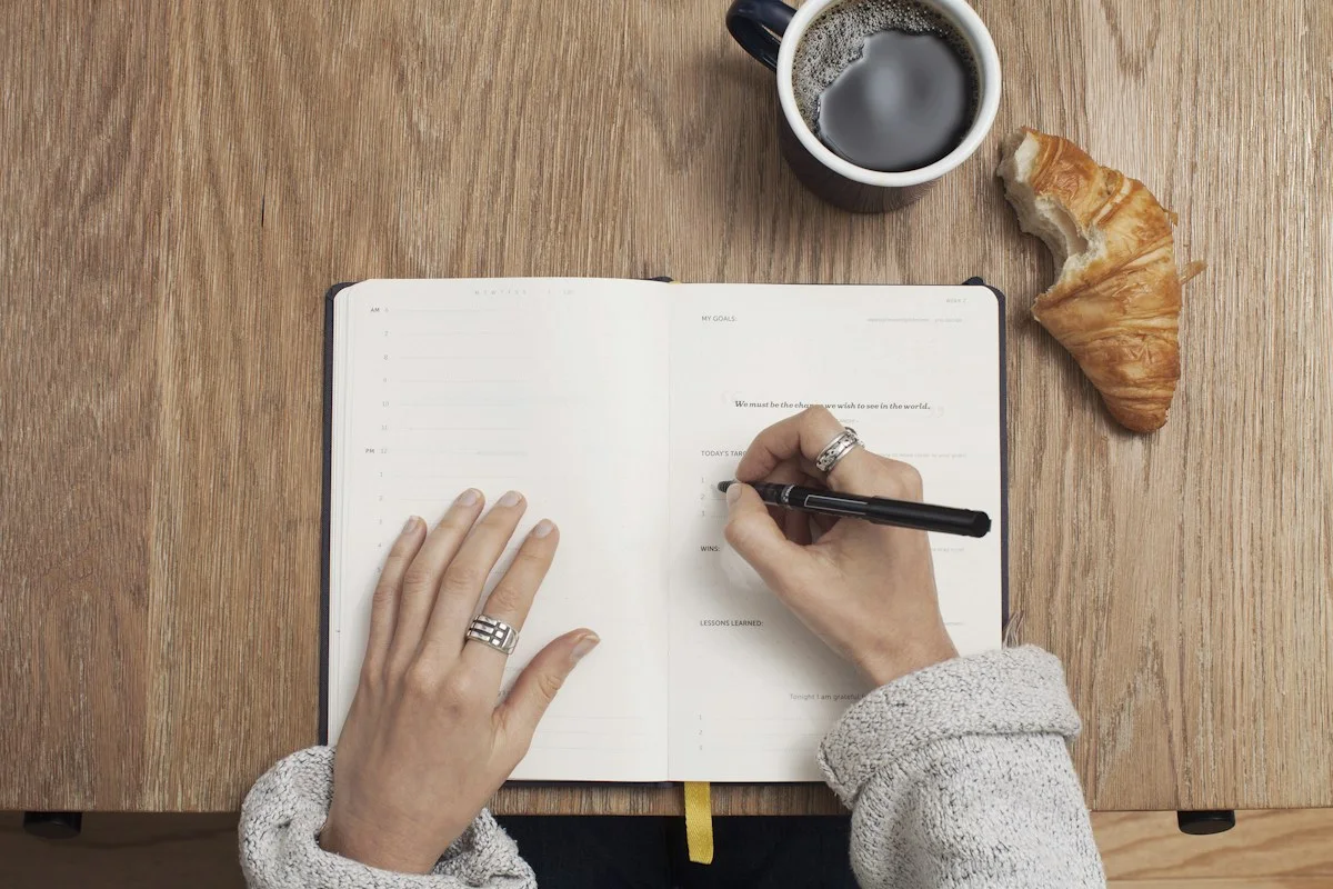 Realistic photograph of an adult literary editor at a wooden desk reading a laptop with books nearby
