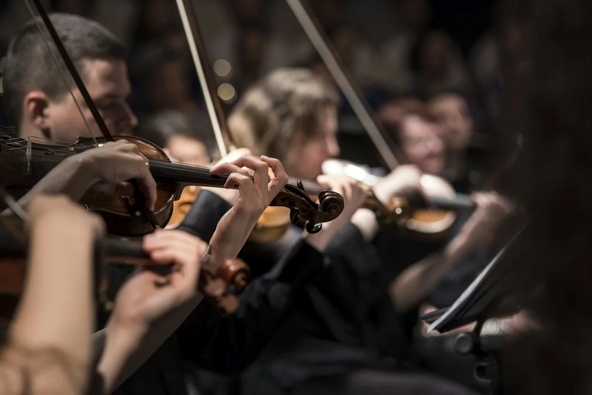 Realistic photograph of an orchestra on a grand concert hall stage seen from the audience, no identifiable people