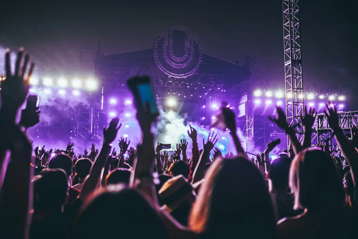 Realistic photograph of a grand British concert hall audience seated in soft warm light, anonymous adults only