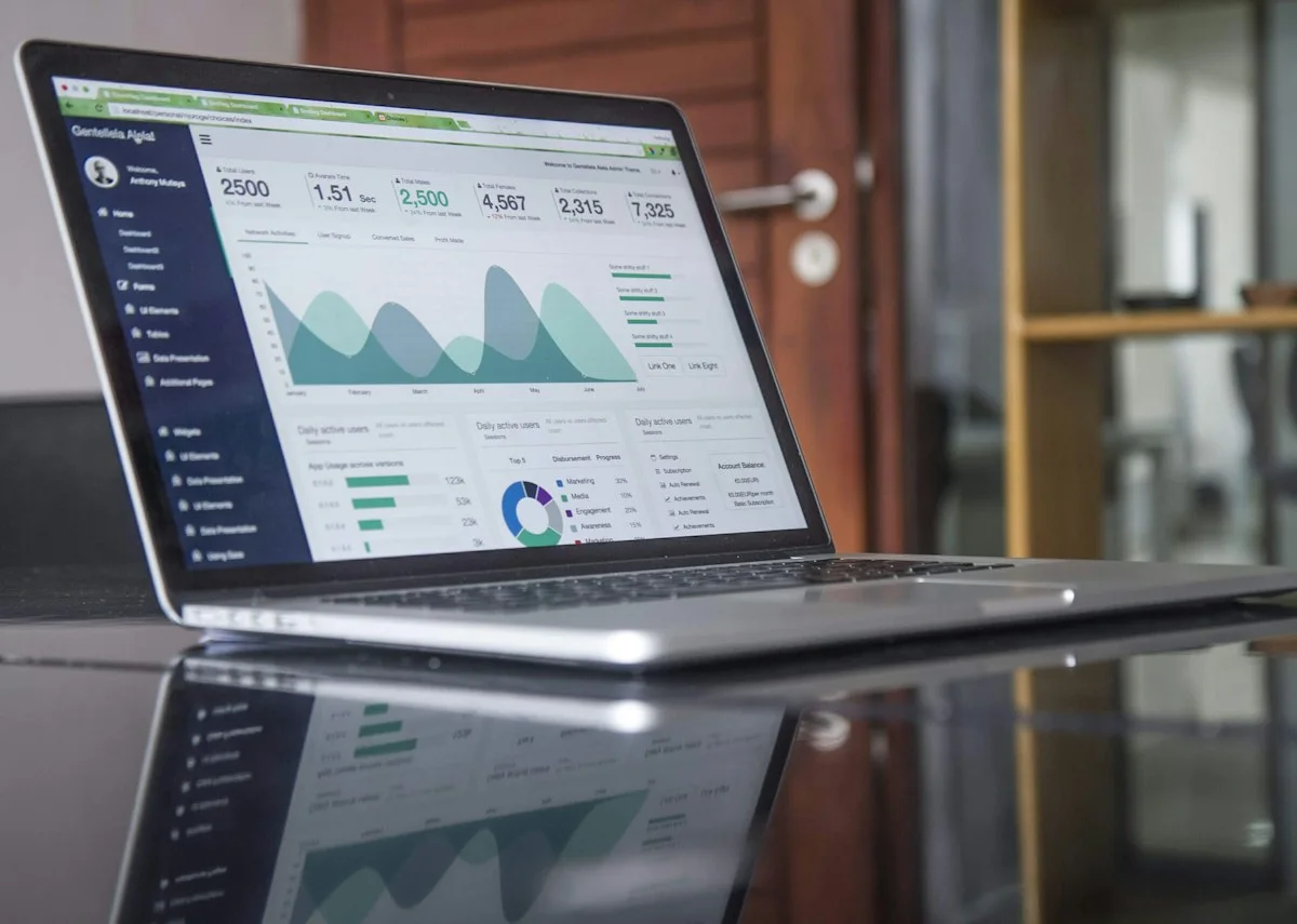 A laptop showing an abstract financial spreadsheet on a British office desk with sticky notes