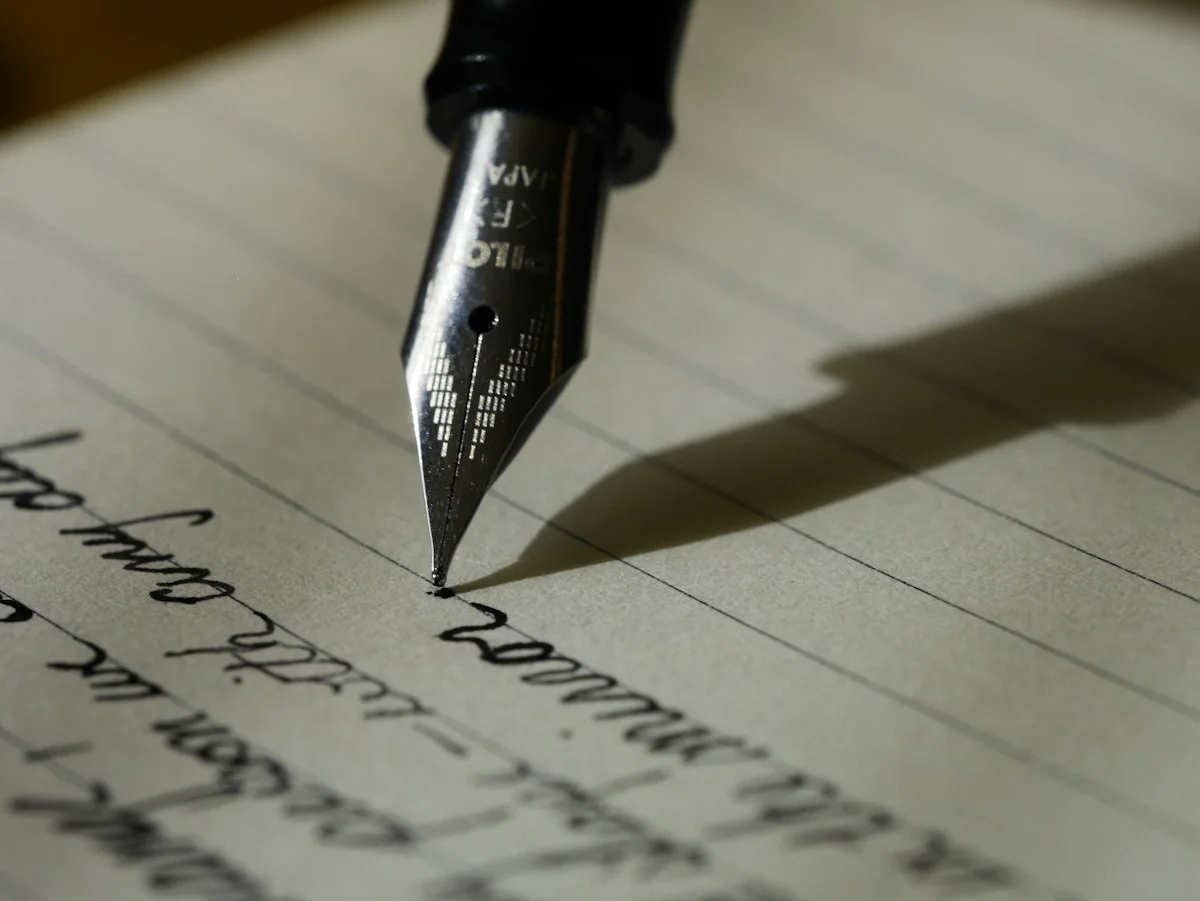 An adult man writing a formal letter at a quiet British home desk